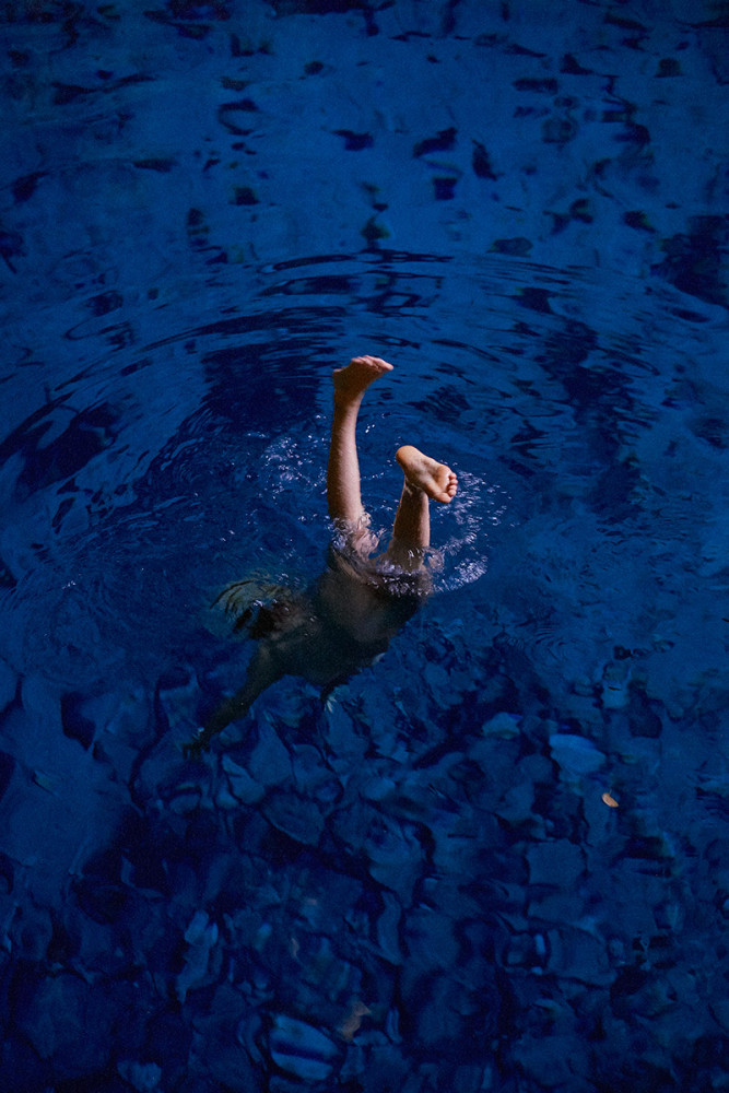Femme plongeant nue dans une eau bleu klein